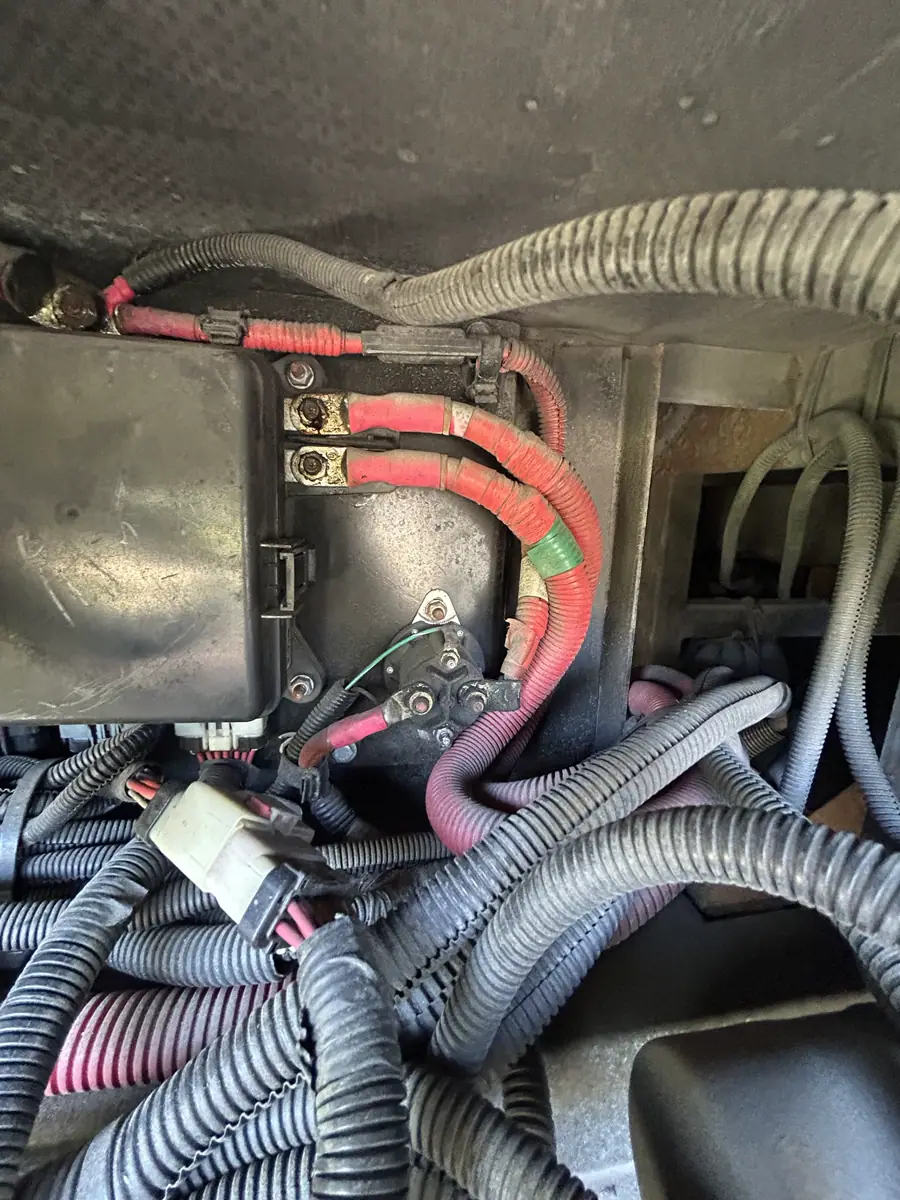 RV chassis electrical bay showing a solenoid, control-module terminals, and bundled protective wire looms.