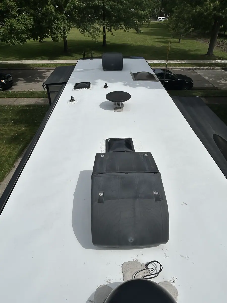 High-angle overview of a white RV roof with air conditioners, vents, and antennas.